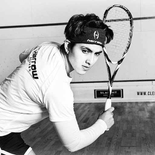 black and white photo of Maria Toorpakai Wazir posing with squash racket while looking off camera, wearing a headband