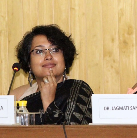 Photo of Payoshni Mitra showing head and shoulders whiles she is sitting on a panel and holding her hand to her chin