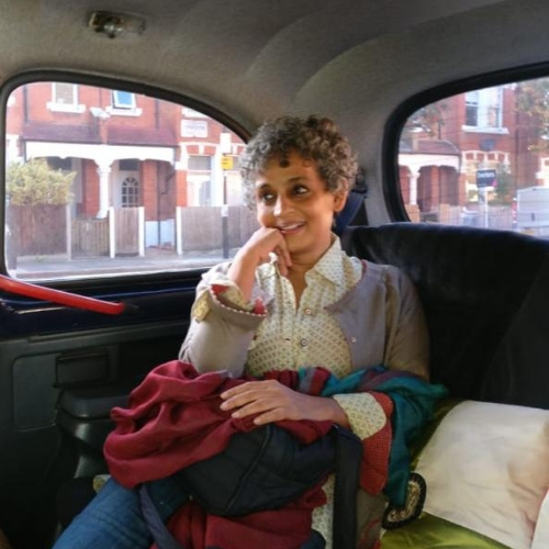 Photo of Arundhati Roy sitting in the backseat of a car with her chin resting on her hand