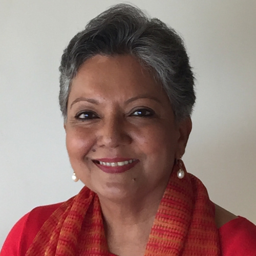 Sri smiling at camera wearing red top and pearl drop earrings